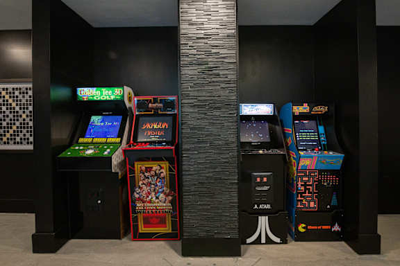A row of Atari arcade games are lined up against a wall.