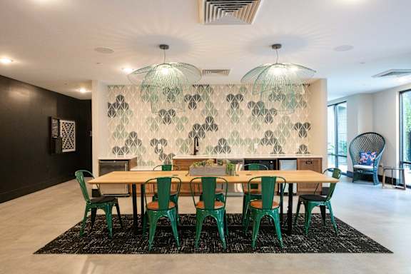A dining room with a table surrounded by green chairs.
