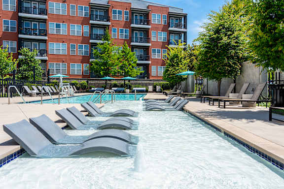 A large swimming pool with lounge chairs and a building in the background.