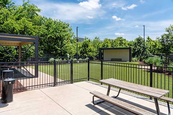 A park bench sits in front of a black fence.