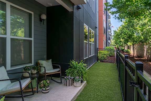 A patio with a chair and a table with a potted plant on it.