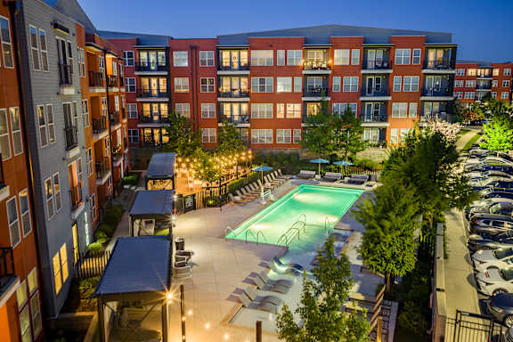 A swimming pool is surrounded by apartment buildings at dusk.
