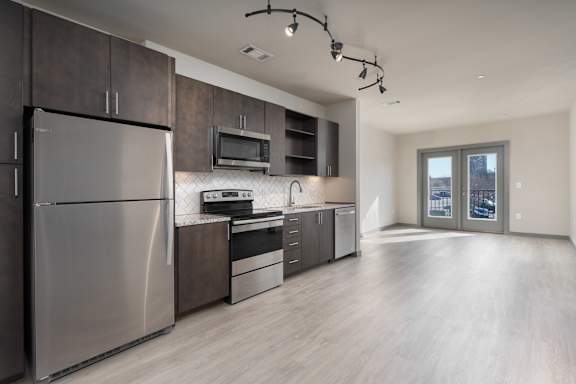 A modern kitchen with a stainless steel refrigerator and wooden cabinets.