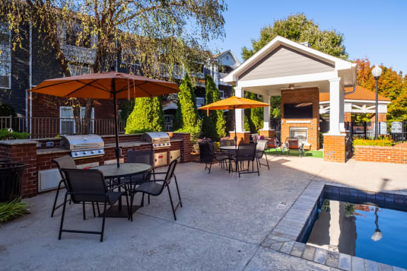 a patio with tables and umbrellas and a swimming pool