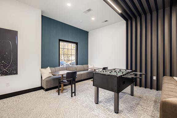 A room with a foosball table and a couch.