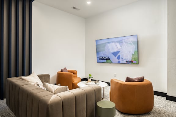 A living room with a large screen on the wall and a brown sofa.