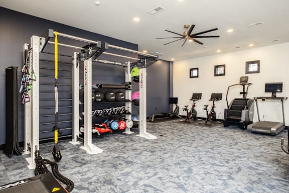 A home gym with a weight rack, exercise equipment, and a fan.