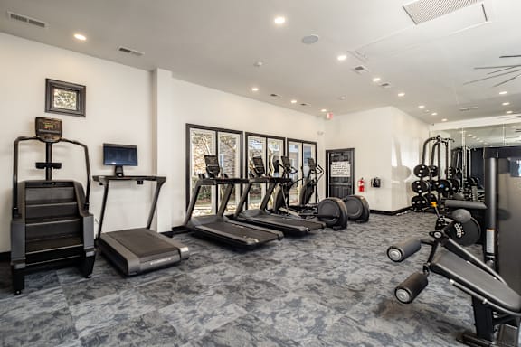 A gym with treadmills, weights, and exercise equipment.
