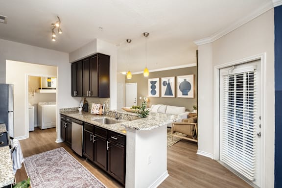 A kitchen with a white island and dark brown cabinets.