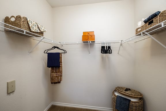 A white closet with a hanging blue shirt and a basket on the floor.