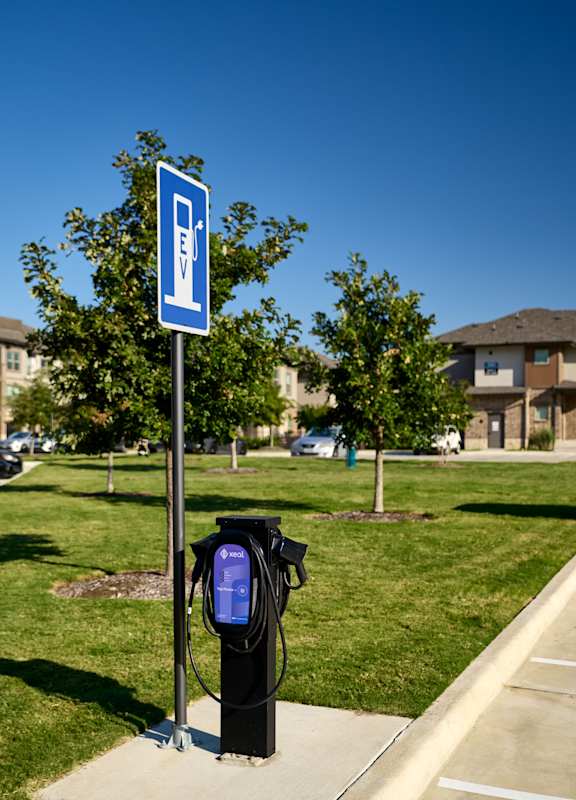 A blue and white sign with a black charging station underneath it.