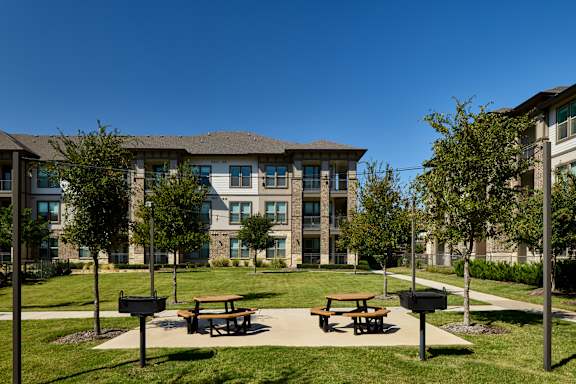 A modern building with a grassy area in front and two picnic tables.