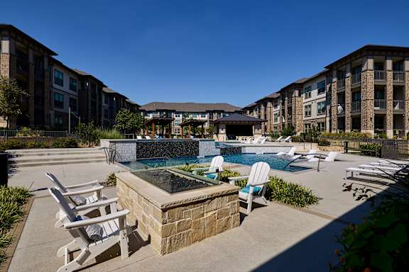 A pool area with chairs and a fountain in the middle.