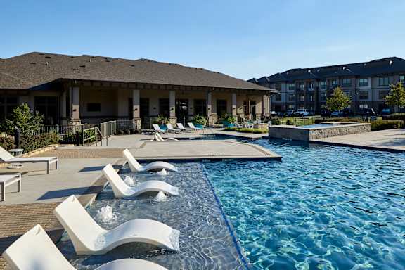 A pool with a blue line and white chairs.