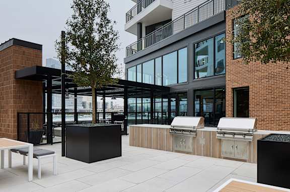 A modern outdoor seating area with a brick wall and a tree.