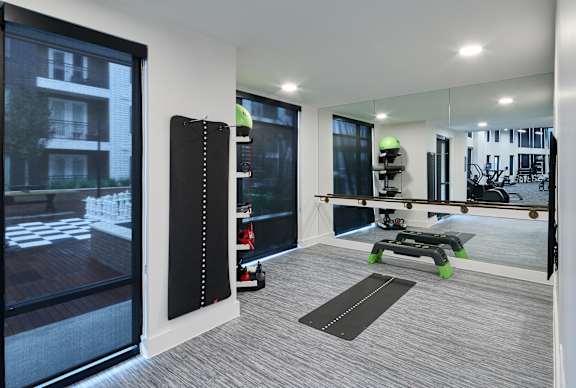 A modern room with a large mirror, a blackboard, and a yoga mat.