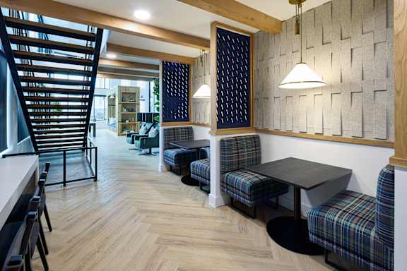 A room with a wooden floor and a wall with a patterned tile design.