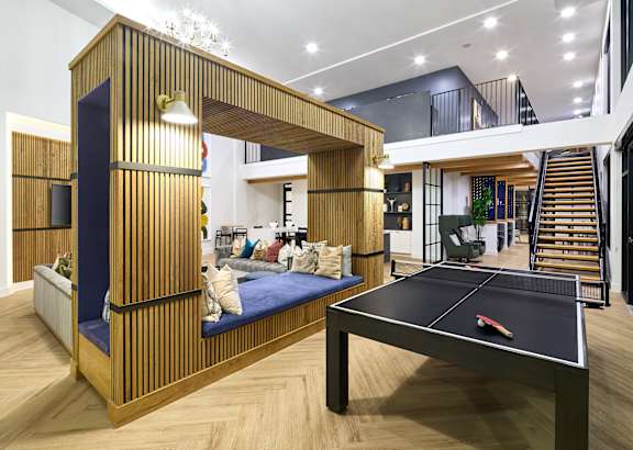 A room with a ping pong table and a couch.