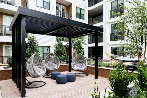 A patio with a black canopy and white wicker chairs.