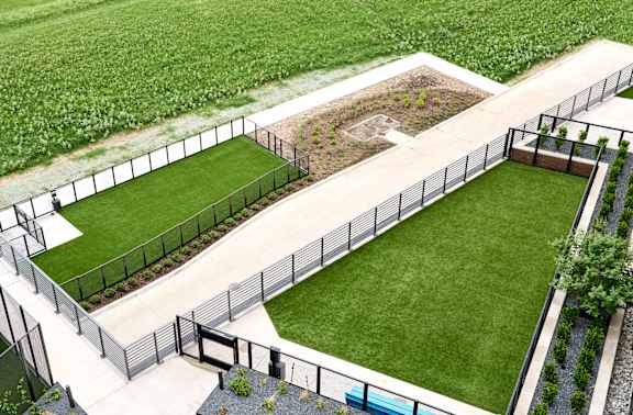 A black fence surrounds a green lawn.