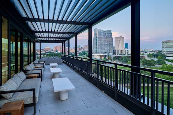 A patio with a black railing and a view of the city.