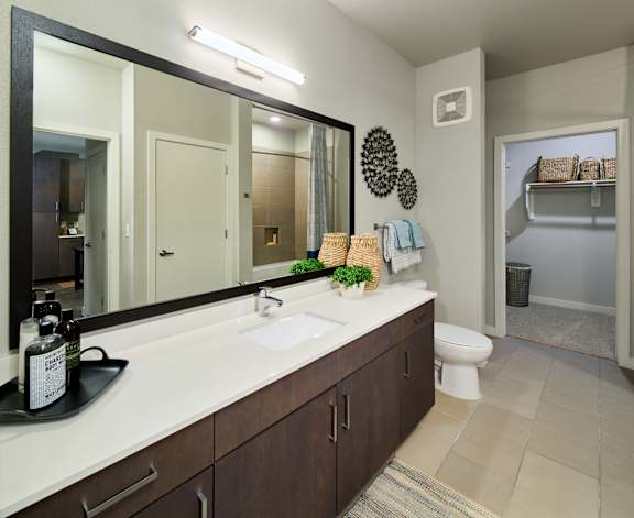A bathroom with a large mirror, a sink, and a toilet.