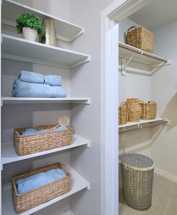 A white closet with baskets and towels.