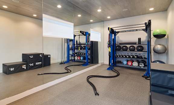 A gym with a variety of equipment including a squat rack, a bench, and a rowing machine.
