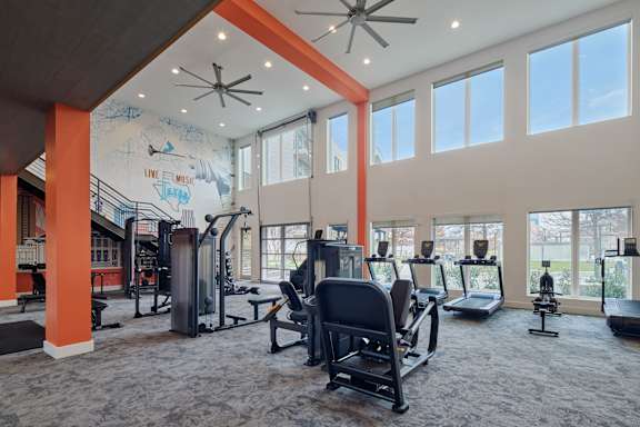 A gym with a variety of equipment including treadmills, weights, and exercise machines.