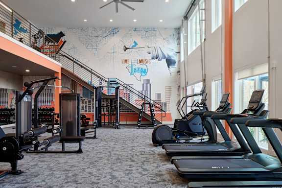 A gym with treadmills, weights and a staircase.