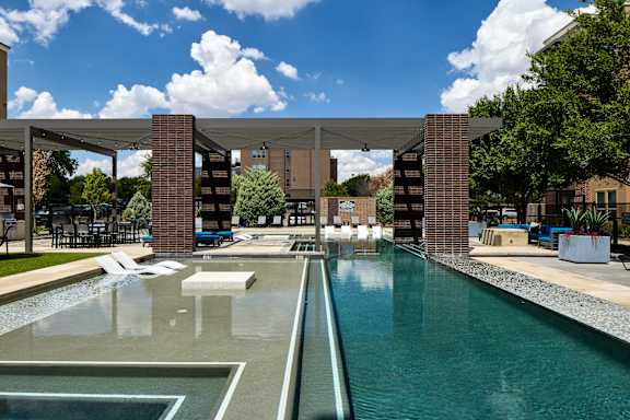 A pool with a water slide and a building in the background.