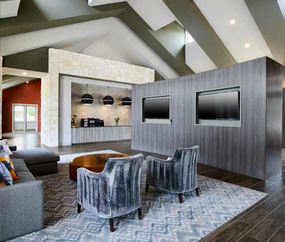 A modern living room with grey chairs and a stone wall.