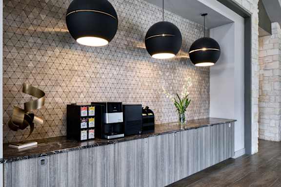 A modern reception area with a wooden counter and black pendant lights.