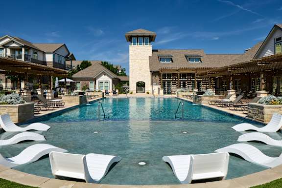A large swimming pool surrounded by white lounge chairs.