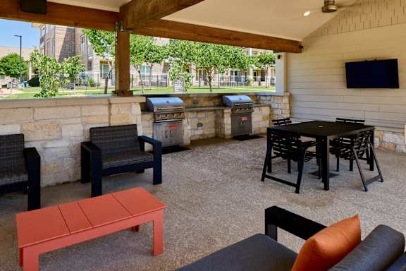 A patio with a table, chairs, and a TV.