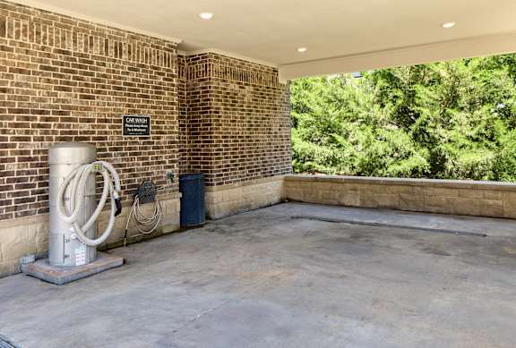 A room with a brick wall and a concrete floor has a sign that says "NO PARKING".