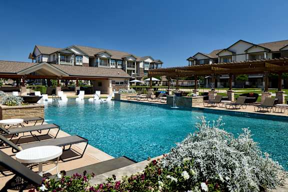 A large swimming pool surrounded by lounge chairs and umbrellas.