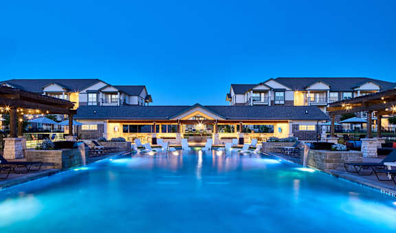 A large, illuminated swimming pool in front of a building.