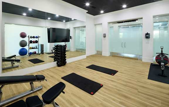 A gym with a variety of equipment including a bench, weights, and a television.