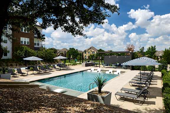 A pool surrounded by lounge chairs and umbrellas.