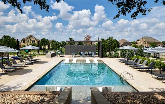 A large swimming pool surrounded by lounge chairs and umbrellas.