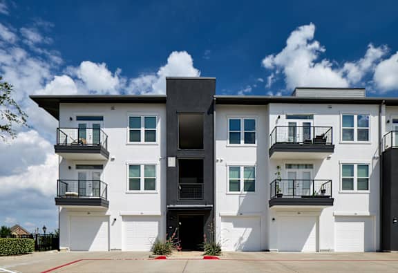 A modern two-story building with white walls and black balconies.
