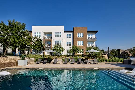 A modern apartment complex with a swimming pool in the foreground.