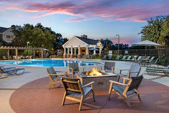 A backyard with a fire pit and chairs.