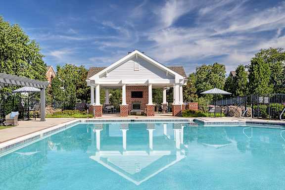 A pool in front of a house with a white roof.