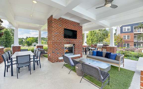A patio with a brick fireplace and furniture.