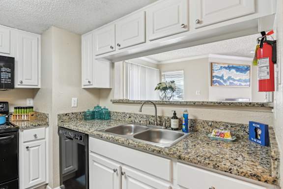 A kitchen with granite countertops and white cabinets at The Glen at Highpoint, Dallas