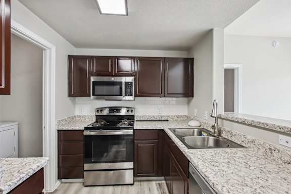 A kitchen with brown cabinets and a stainless steel oven at Sweetwater At Metro North Apartments, Phoenix