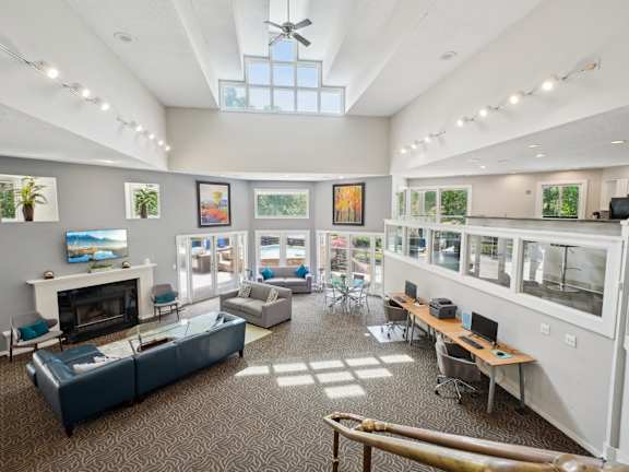 A spacious room with a fireplace, couches, and a ceiling fan.