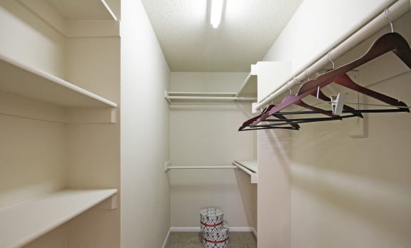 a spacious walk in closet with white shelves